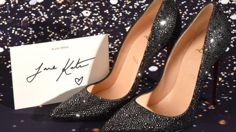 A pair of silver and black high heels encrusted with crystals with a note from Kate Moss