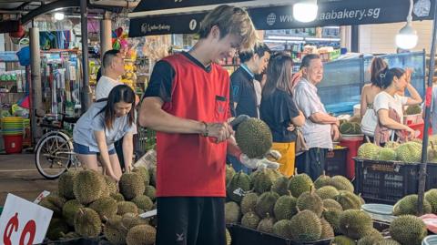A fruit seller cutting durian at a stall