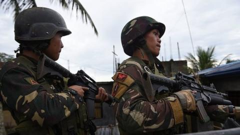 Philippine soldiers stand guard aboard their truck as they escort rescue workers after evacuating trapped residents from their homes on the outskirts of Marawi on the southern island of Mindanao on May 31, 2017