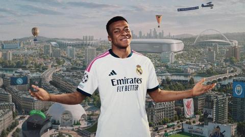 Kylian Mbappé is pictured wearing his Real Madrid strip, smiling, in front of a cityscape backdrop featuring dozens of references to different football teams and players. Flags for Manchester City and Liverpool and a mural depicting Zlatan Ibrahimovich are among the immediately obivious references..