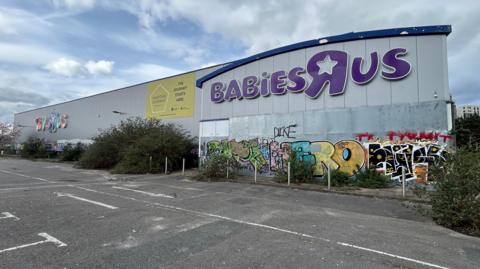 Southampton's former Toys R Us site - the building is derelict with graffiti and vegetation growing wildly around the building and its car park.