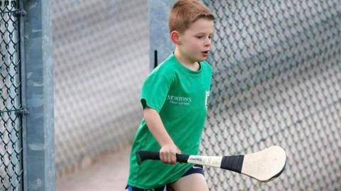 Joseph Hegarty in a green t-shirt with a hurling stick