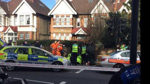 The scene of the crash. A road with police tape, emergency service workers and police cars