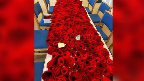 Thousands of knitted poppy flowers all laid out to create a waterfall feature at All Saints' Church in Brailsford