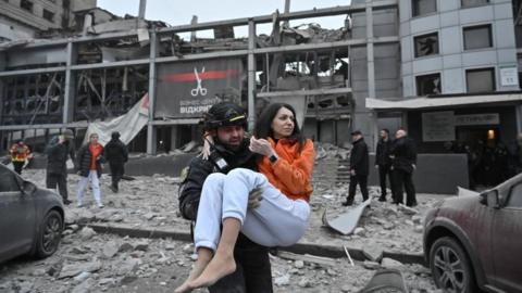 A Ukrainian police officer evacuates a woman from a building destroyed by a Russian missile strike in Zaporizhzhia, southern Ukraine. Photo: 10 December 2024