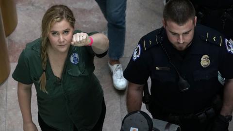 Comedian Amy Schumer (L) is led away after she was arrested during a protest against the confirmation of Supreme Court nominee Judge Brett Kavanaugh