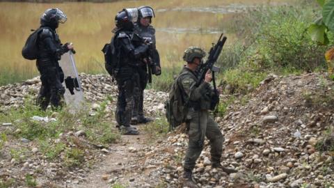 Colombian soldiers and riot police stand guard at an illegal gold mining place in Triangulo de Telembi, Colombia on January 25, 2023.