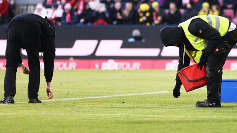 Stadium staff clearing up rubbish on the pitch