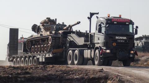 A photo made available by the Dogan New Agency shows Turkish military trucks transporting a tank to the border with Syria near Sanilurfa on 16 January 2018