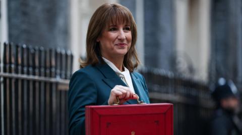 Chancellor Rachel Reeves standing in Downing Street with her Budget red box.
