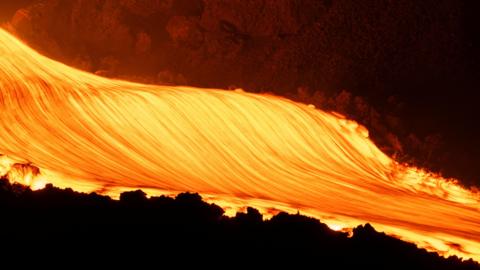Molten lava flows down the slope of Mount Etna during an eruption.