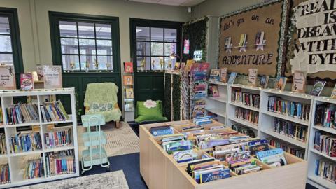 The picture shows multiple book shelves with hundreds of colourful books.