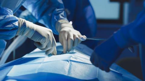 Close-up of surgeon with nurse and and assistant during operation. - stock photo