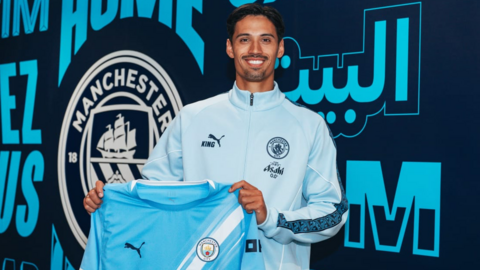 Tijjani Reijnders holding a Manchester City home shirt