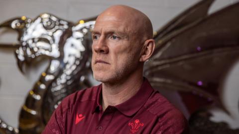 Wales senior mens head coach Steve Tandy poses for photographs in front of a dragon image