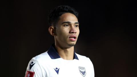 Marselino Ferdinan standing on the pitch wearing Oxford United kit