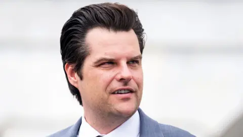 Close up of Matt Gaetz looking to the right. He has dark, short hair.