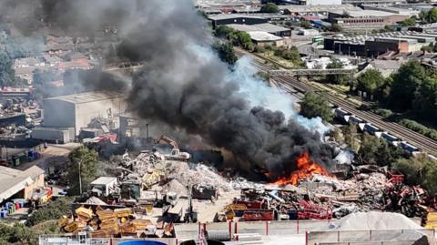 Drone shot of flames and smoke coming from an industrial yard.