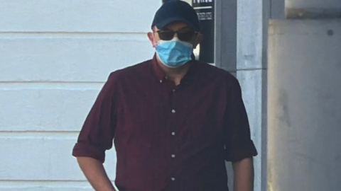 Buckley is wearing a face mask, dark sunglasses and a dark peaked cap.