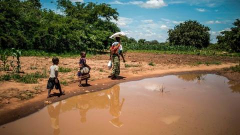 A mother and her children walk back home after collecting food from a distribution organized by the World Food Programme (WFP) n Simumbwe, Zambia, on January 22, 2020