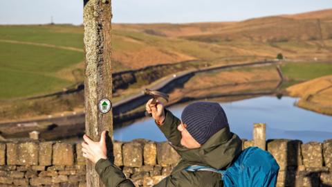 Man nailing a way marker to a post