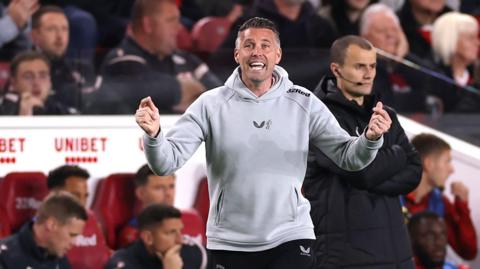 Rob Edwards with his arms outstretched, makes a tactical point to his Middlesbrough players during the draw with Stoke