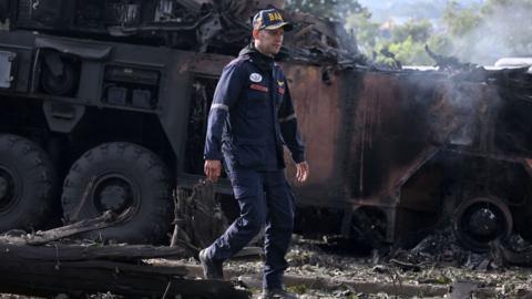 A firefighters passes by a burnt military vehicle at La Carlota air base in Caracas on January 3, 2026, after US forces captured Venezuelan leader Nicolas Maduro after launching a "large scale strike" on the South American country. 