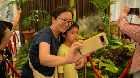 Two visitors pose for a selfie in front of Amorphophallus titanum, famously known as the Corpse Flower seen at the Royal Botanic Garden Sydney