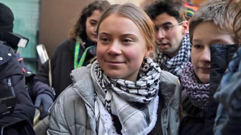 Greta Thunberg smiling as she made her way past photographers