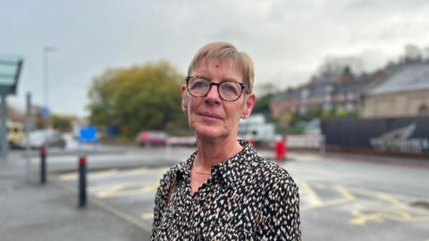 A woman standing outside of St. Oswald's Hospital in Ashbourne, Derbyshire.