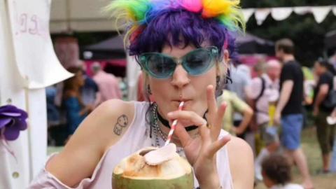 A woman drinking from a coconut shell at the 2022 Bedford River Festival