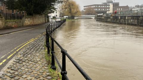 A brown river very close to spilling onto a road.