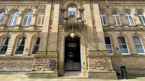 A large beige building with pillars on either side of a large doorway