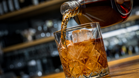 Whiskey pouring into a crystal glass with ice