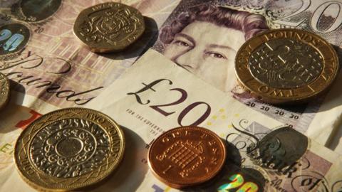 A close up of sterling pound notes and coins.