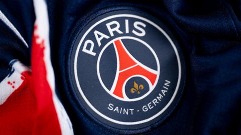 A detail of Paris St-Germain's badge on a blue football shirt with red trim