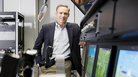 Kelly Ortberg stands by a row of computers at the Rockwell Collins production facility in 2016