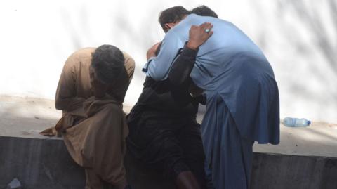 Relatives of the victims of a blast at a railway station hug as they wait at a hospital, in Quetta, the provincial capital of restive Balochistan province, Pakistan