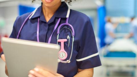 A nurse holds a clipboard