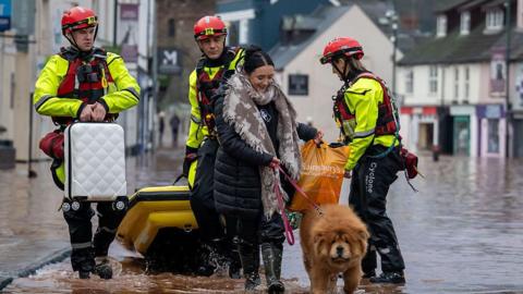 A woman and her dog being helped by emergency service workers in Monmouth.