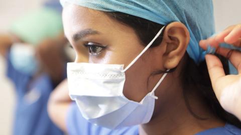 A female medical professional wearing a face mask and other personal protective equipment