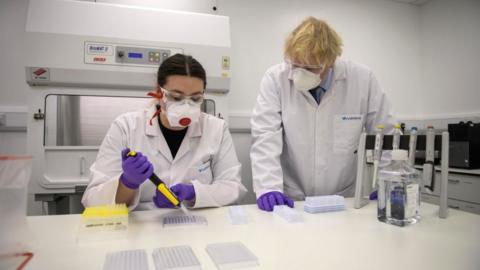 Boris Johnson tries his hand at one of the tests with Kerri Symington, quality control technician as he visits the French biotechnology laboratory Valneva in Livingston where they will be producing a Covid 19 vaccine on a large scale