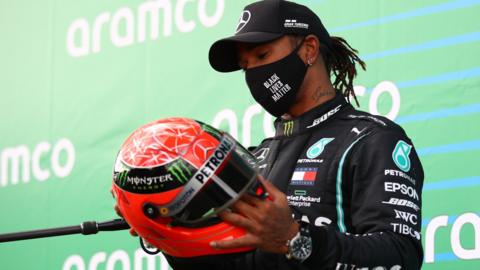 Lewis Hamilton holds Michael Schumacher's race helmet