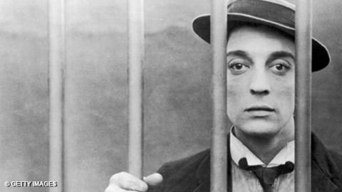 Buster Keaton poses behind bars.