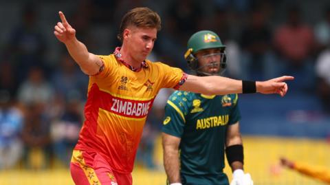 Brad Evans of Zimbabwe celebrates the wicket of Travis Head of Australia as Glenn Maxwell watches on from the non-striker's end