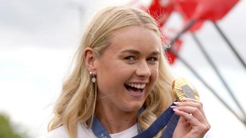 Hannah Scottt smiles holding up her Olympic gold medal