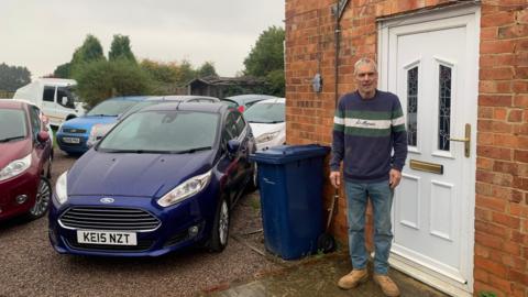 Andrew Smith standing beside some of his Ford Fiestas he keeps outside his house.