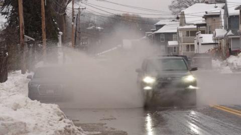 An SUV hits a large puddle shooting up a spray of wintry mix in a small US town.