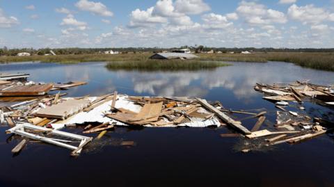 Bits of wood from a destroyed home float on flooded marshland