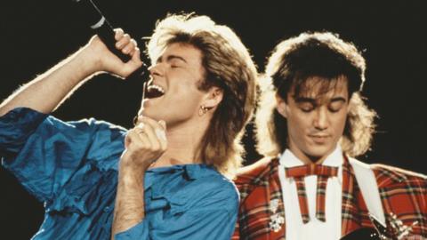 George Michael (left) and Andrew Ridgeley of Wham! performing together live on stage during the pop duo's 1985 world tour